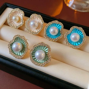 Détail de boucles d'oreilles perles en forme de fleur avec dorure et émail dans un écrin