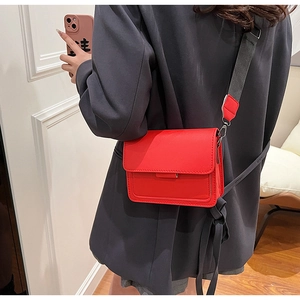 Detail of red vintage crossbody square bag with wide fabric strap on a grey blazer