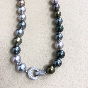 Detailed macro view of Tahitian pearl necklace with multi-colored luster and diamond clasp