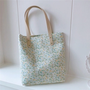 Close-up of floral cotton tote bag with green flower pattern and brown leather straps