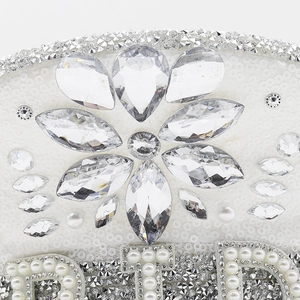 Détail du logo BRIDE orné de cristaux et paillettes sur un chapeau de fête blanc