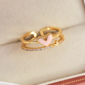 Macro shot of double-layer gold flower heart ring with pink enamel and pavé zircons