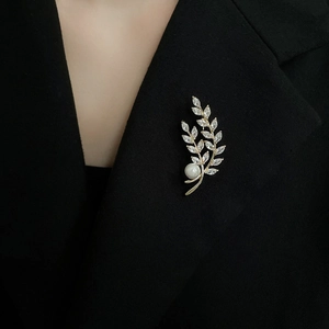 Detail of gold wheat stalk brooch with zircon and pearl on a black suit lapel