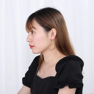 Detailed view of large gold heart-shaped hoop earrings worn by a model in a side profile