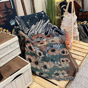 Detail of woven camping blanket featuring sunflower and mountain jacquard with fringe