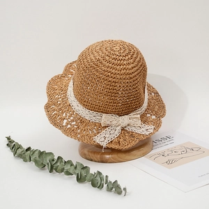 Detail of baby straw hat featuring delicate lace bow and wavy brim in rural style