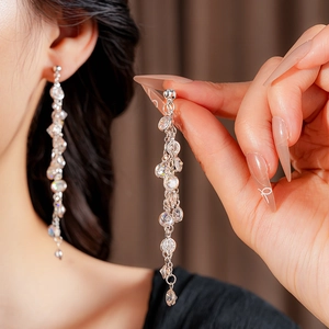 Close-up of sparkling silver tassel earrings with round cubic zirconia on model