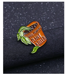 Gros plan d'un pin's émaillé Well-Meaning Plant Killer montrant le pot orange et les feuilles