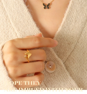 Detail of bohemian butterfly necklace and matte gold ring with zircon on a model