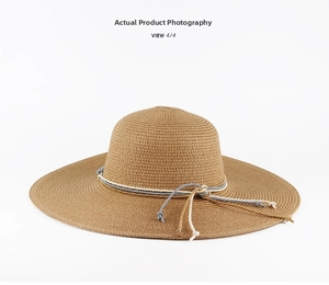 Close-up of a khaki straw sun hat featuring a decorative three-color braided ribbon strap