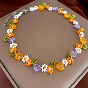 Detail of colorful flower beaded necklace with a silver lobster clasp on a beige tray