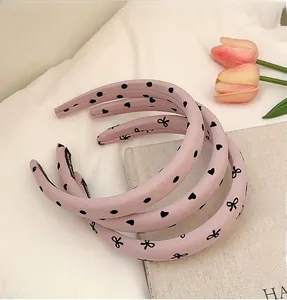 Three-piece set of pink padded headbands with black heart patterns and neat side stitching