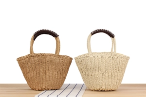 Detail of hand-woven straw handbags with contrasting leather handles and stitching
