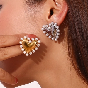Golden and silver heart stud earrings with pearl trim shown on model for women