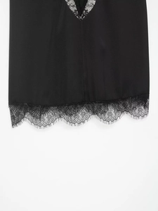 Détail d'un caraco en soie noire avec bordure en dentelle délicate sur l'ourlet bas