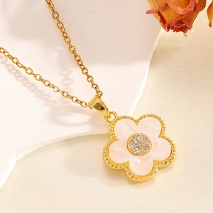 Détail du pendentif fleur dorée avec pétales blancs et pierre en zircone brillante