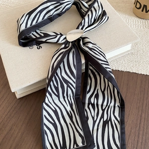 Detail of zebra pattern silk scarf with a silver oval metal ring buckle on a book