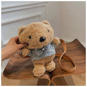 Detail view of a cute brown plush teddy bear crossbody bag wearing a grey hoodie on a chair