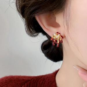 Close-up of model wearing 18k gold plated firework stud earrings with red zircon accents