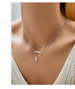 Close-up of double layer silver necklace featuring a sparkling cross and circle pendant
