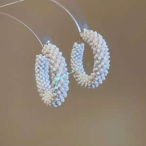 Macro shot of circular hoop earrings with micro pearls and iridescent crystal details