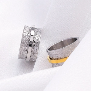 Detail of floral engraved spinning rings in silver and gold on white silk background