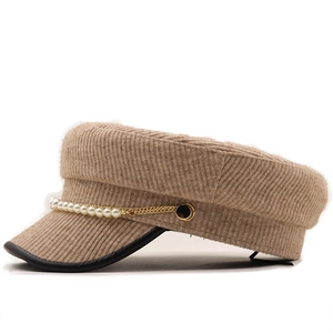 Detailed view of beige knit newsboy cap with pearl gold chain and leather trim