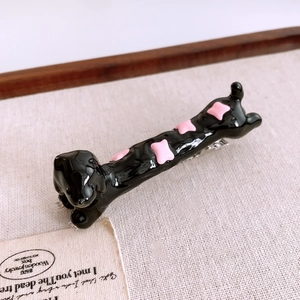 Detail of black resin dachshund hair clip with pink star patterns and metal clip base