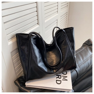 Détail d'un grand sac cabas noir avec texture en cuir froissé sur un canapé