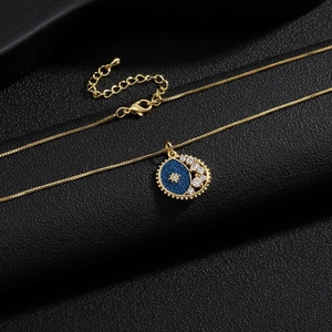 Detail of gold star and moon pendant with blue enamel and zircon inlay on black leather