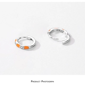 Macro detail of silver S925 earrings with orange enamel inlay and clear zircon stones