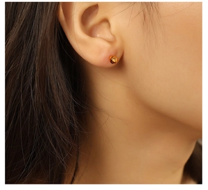 Detailed view of golden ball stud earrings with hammered texture on ear