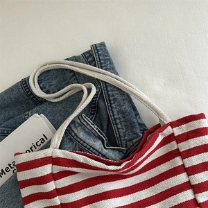 Minimalist red and white striped canvas tote bag displayed on blue jeans for daily use