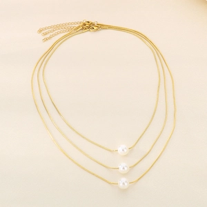 Detailed view of three layered gold snake chains with central white pearls and lobster clasp