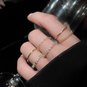 Close-up of gold-plated zircon rings set on a model holding a glass in elegant lighting