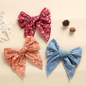 Close-up of three floral print cotton bow hair clips in red, orange, and blue colors