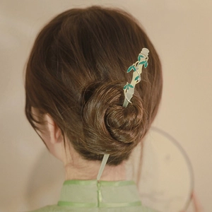 Nahaufnahme einer Haarnadel mit Maiglöckchen-Quaste in einem klassischen Dutt-Haarstyling