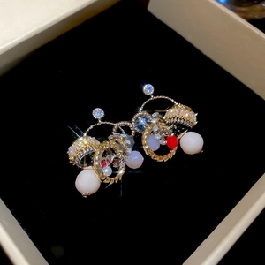 Close-up of tassel earrings with zircon, opal beads, and red accents in a jewelry box