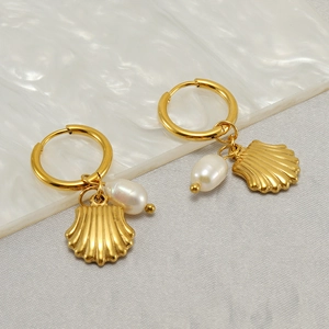 Elegant gold hoop earrings with natural pearl and shell charms on marble background