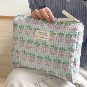 Close-up of quilted blue plaid cosmetic bag with pink floral print and beige label
