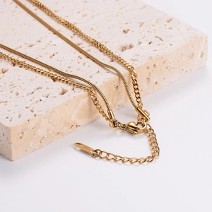 Double-layered gold chain necklace with snake bone design on stone pedestal