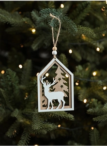 Detailed view of laser-cut wooden house ornament hanging on a Christmas tree branch