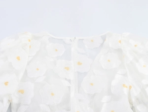 Detail of white puff sleeve dress featuring floral embroidery and hidden back zipper