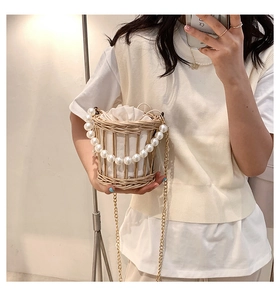 Mirror selfie showing a straw bucket bag with pearl handle and metal chain strap