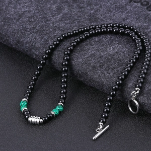Detail of beaded necklace featuring black stones and green malachite with silver T-bar clasp