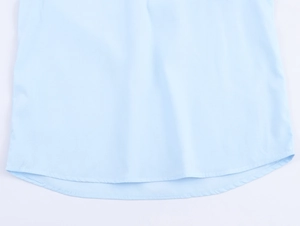 Detail of light blue shirt showing curved hemline and precise double stitching work
