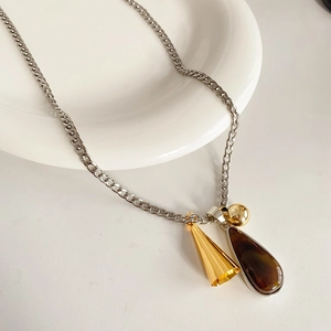 Detail of titanium steel necklace with gold cone, ball, and brown resin teardrop pendants