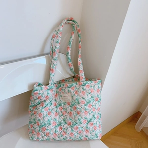 Detail of floral quilted cotton tote bag with French label on minimalist white chair