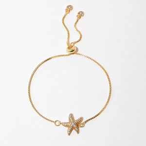 Close-up of a gold starfish bracelet with sparkling zircon stones and an adjustable box chain