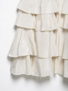 Detailed close-up of champagne layered ruffle fabric with frayed edges and silk texture